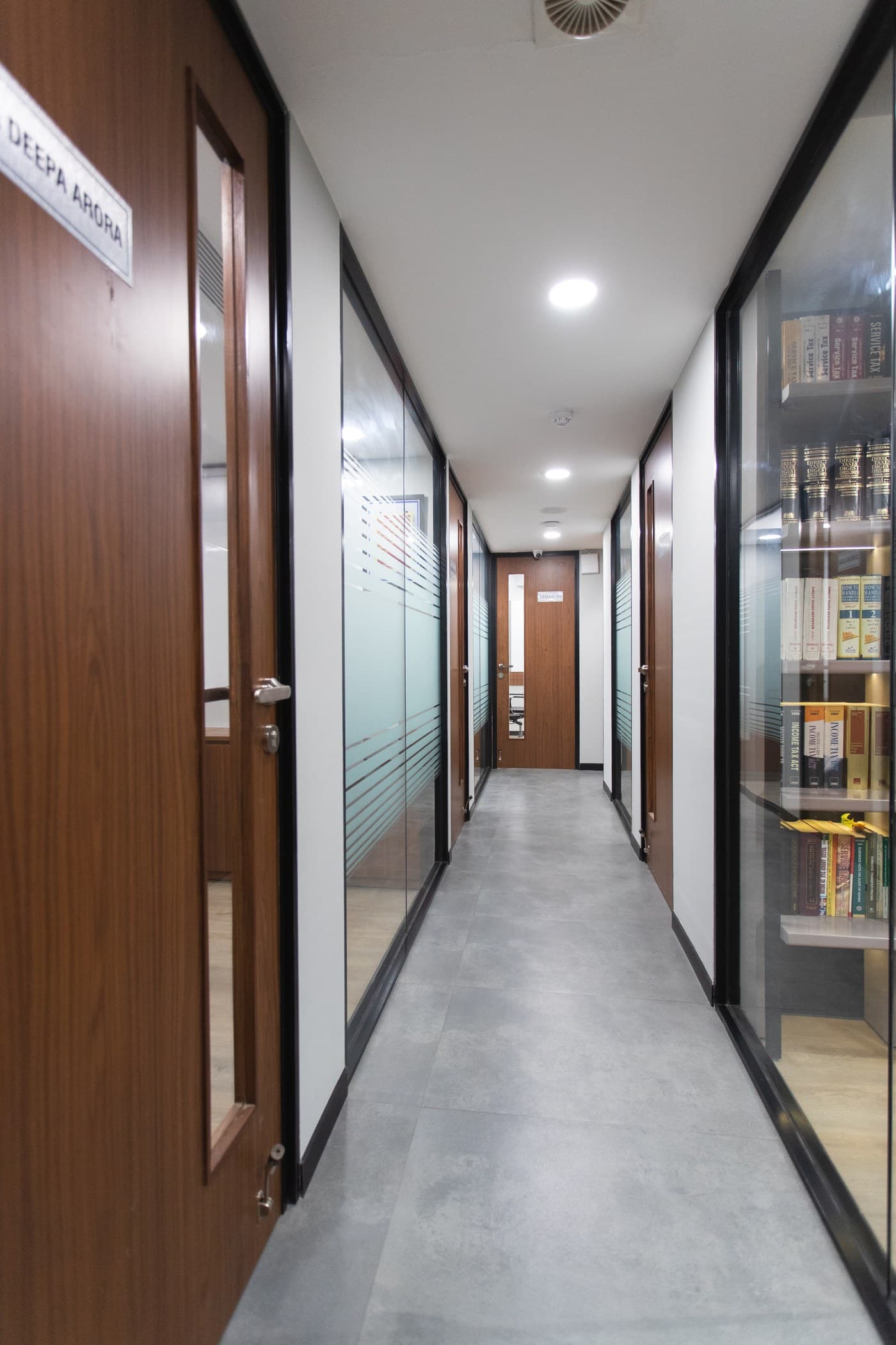 Corridor of glass-partitioned offices beside a shelf of law books