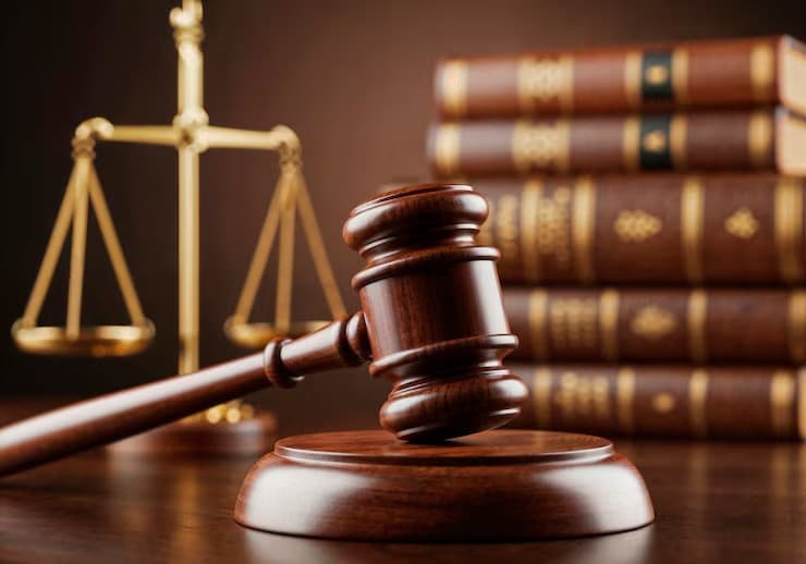 Gavel and brass scales in front of a stack of bound law books