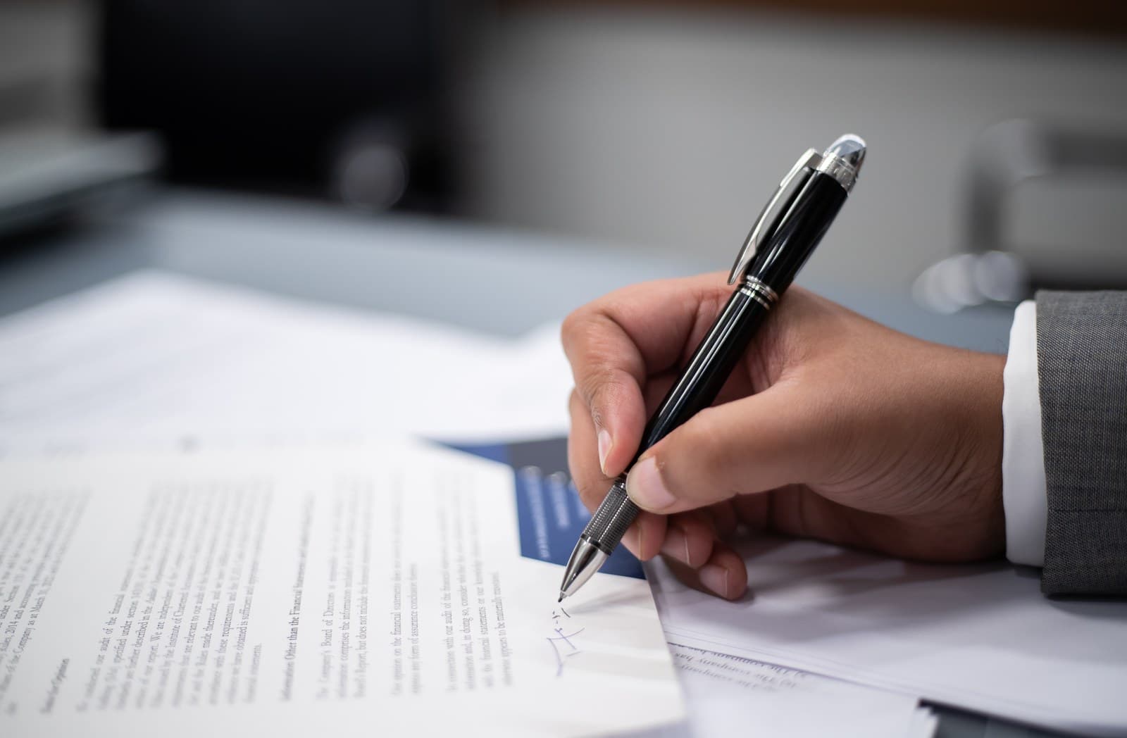 Close-up of a hand signing a document with a pen