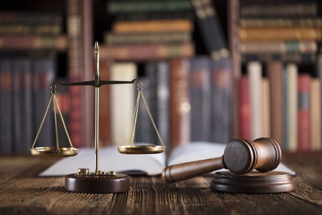 Scales of justice and a gavel in front of a shelf of law books